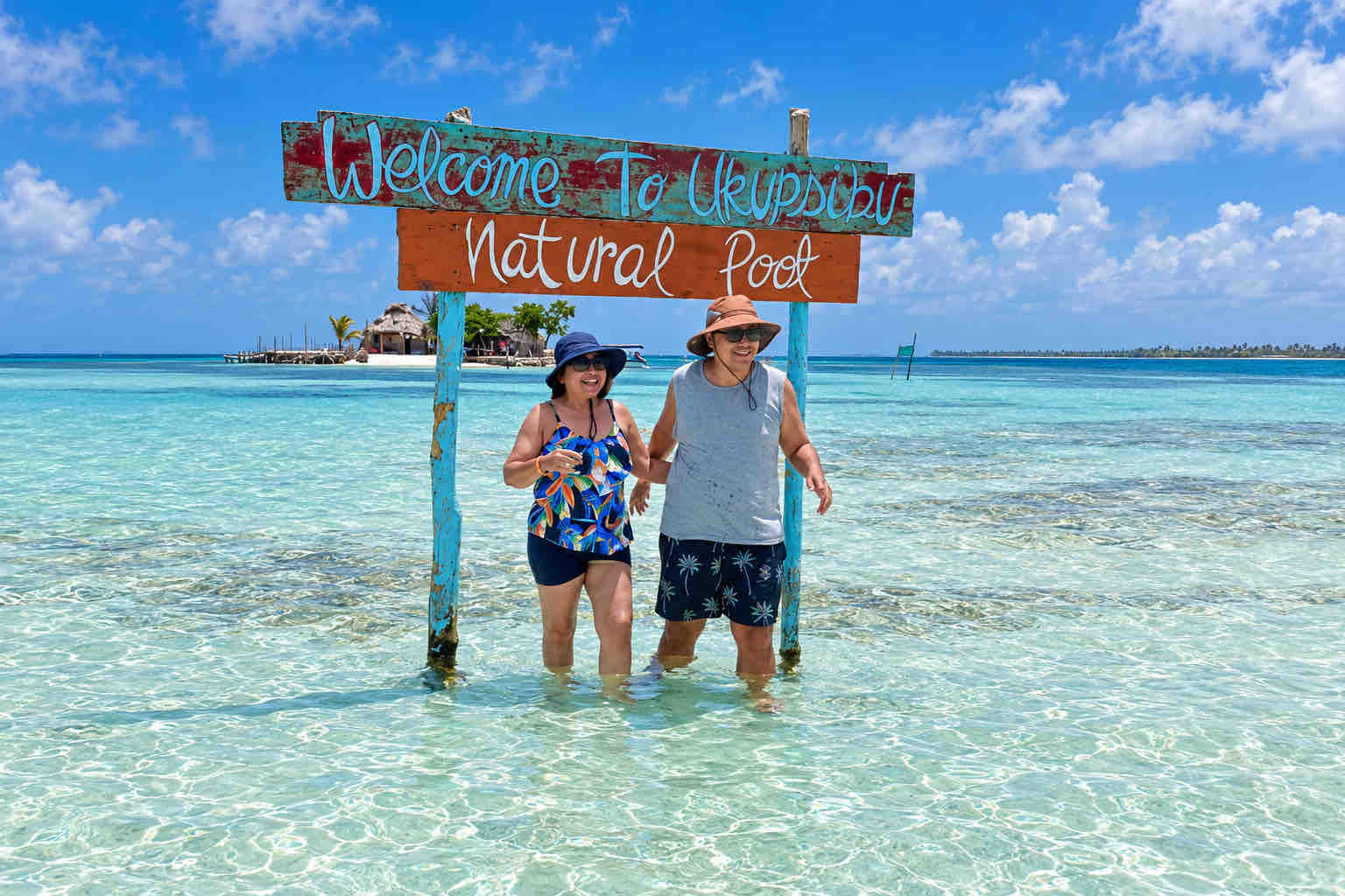 Two travelers standing beneath a natural pool sign during a San Blas tour.