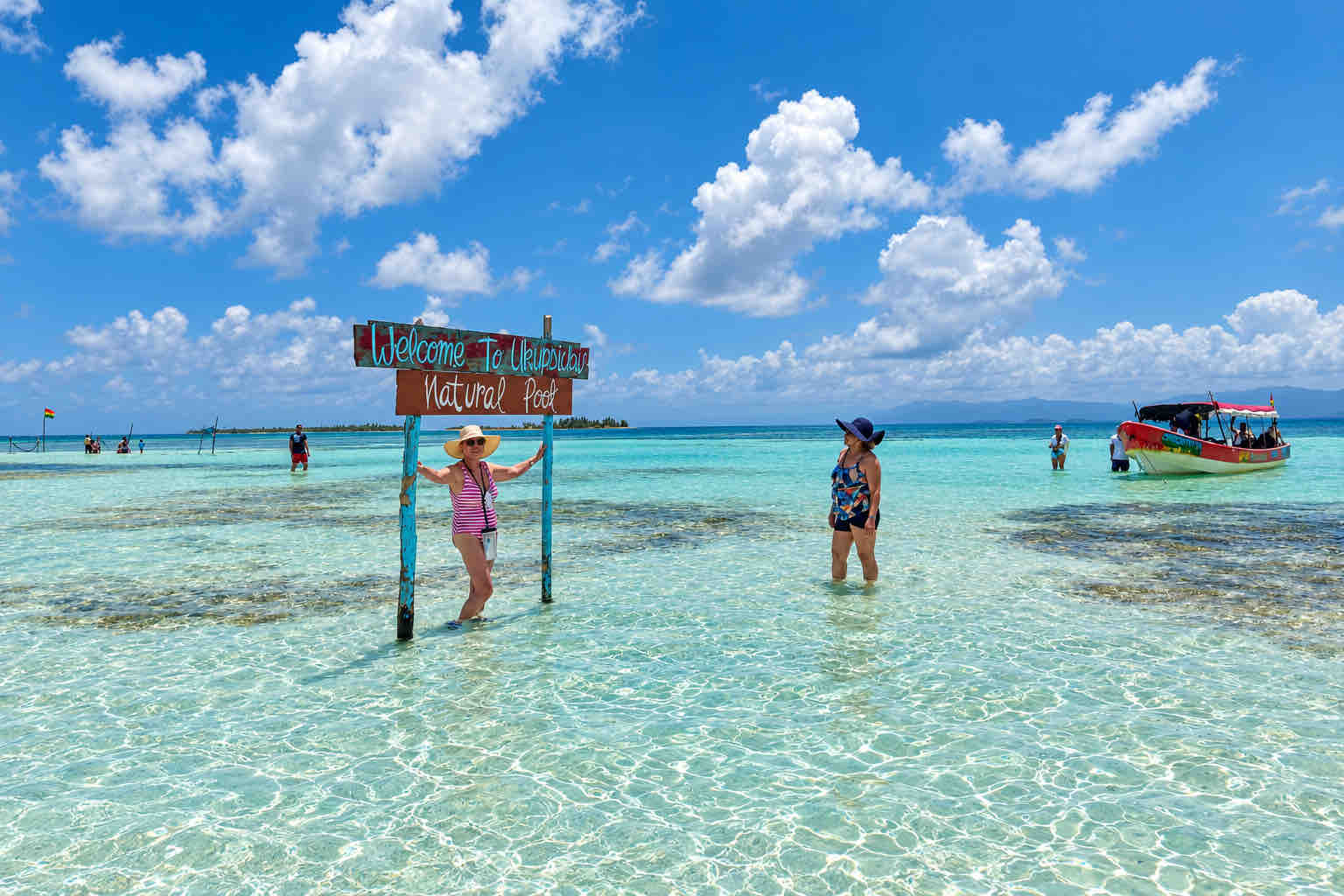 Two travelers beside a natural pool sign in the clear shallows of San Blas.