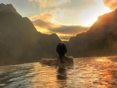 Woman in infinity pool at sunset in Mexico looking at mountains