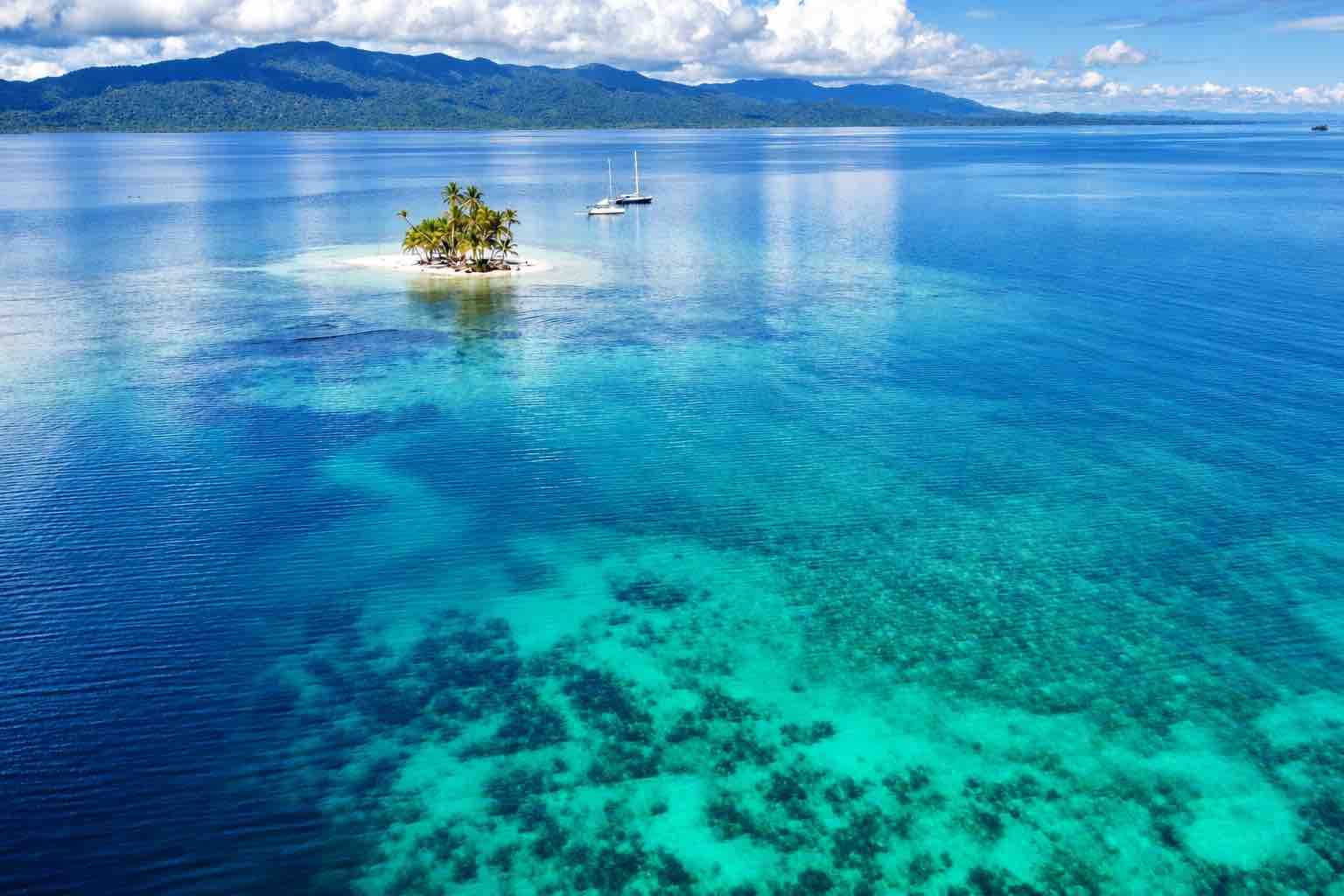 Aerial view of a small San Blas island, sailboats and turquoise Caribbean water