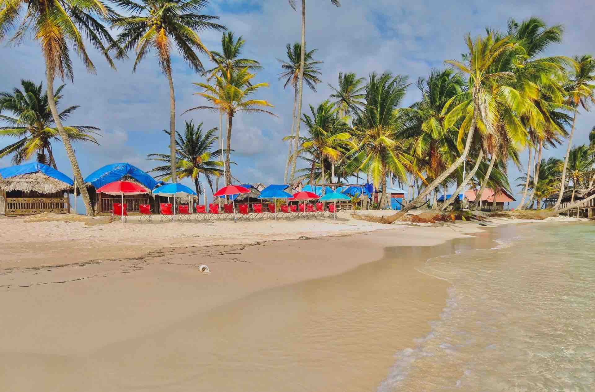 San Blas Isla Guanidup island palm trees red beach chairs