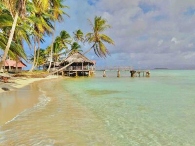 San Blas island beach with palm trees, dock and wood cabin