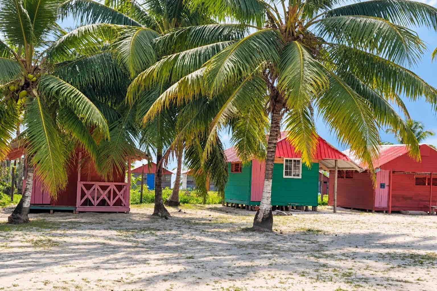 Private cabins with shared bathrooms beneath palm trees on Isla Diablo San Blas