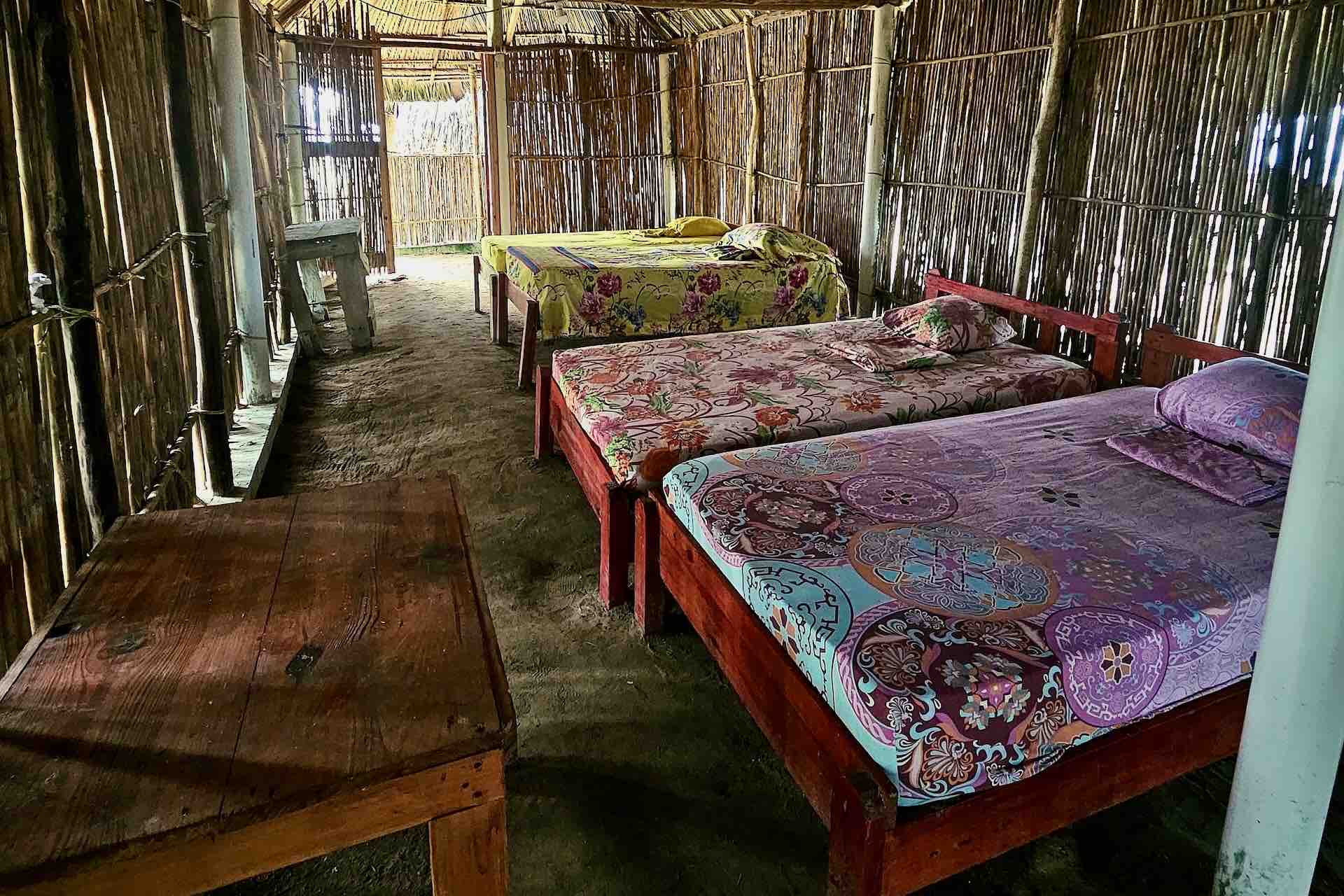 Inside a shared cabin with beds and sand floor at Isla Asserya in San Blas, Panama