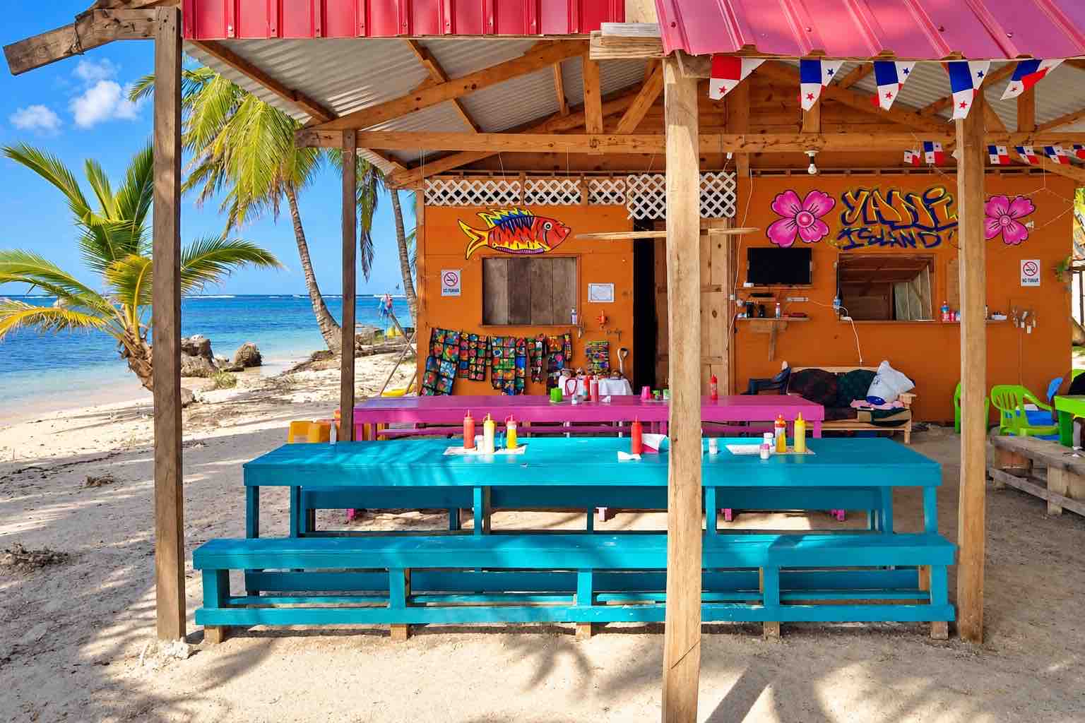 Colorful open-air dining tables beside a San Blas beach
