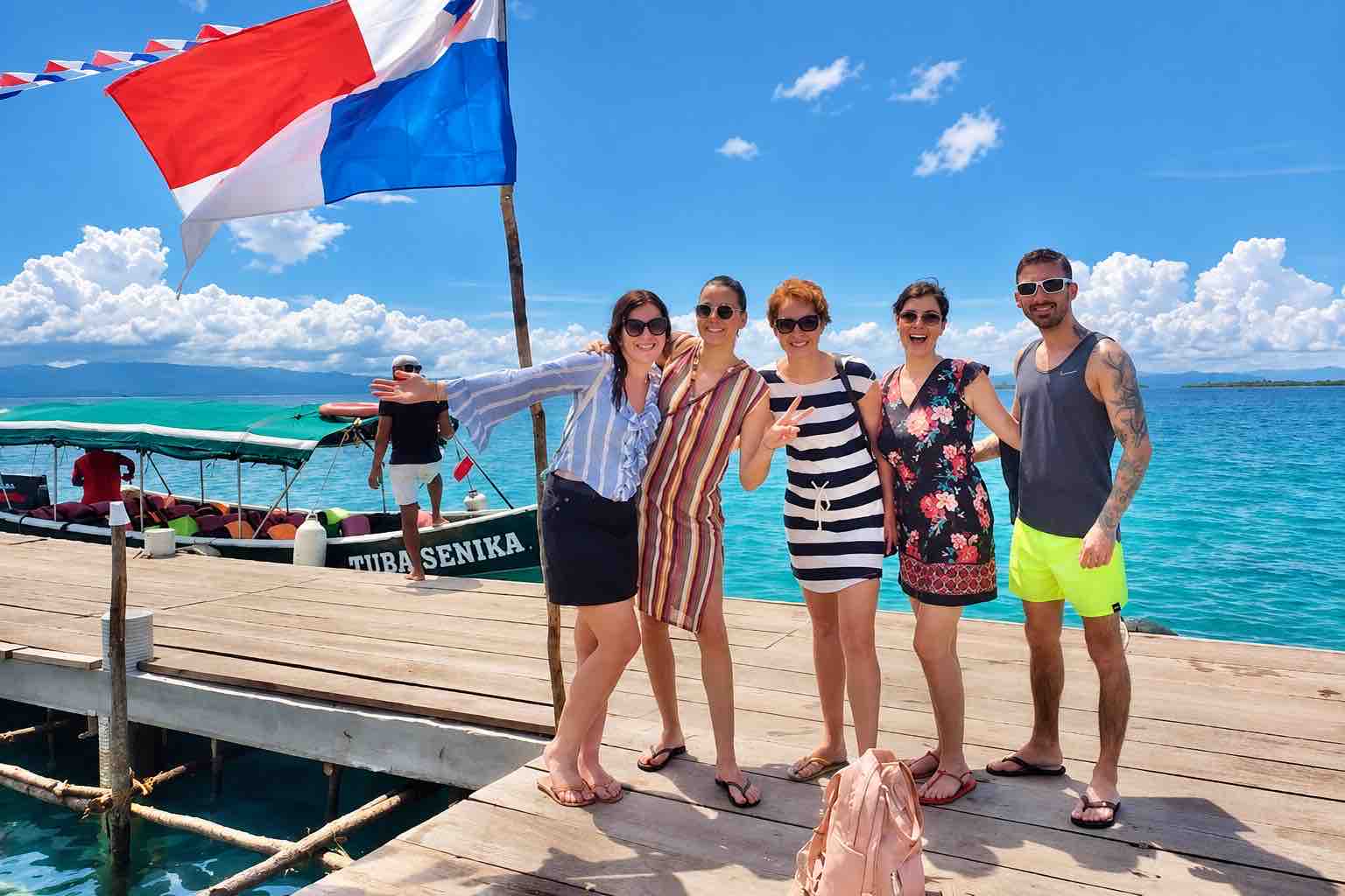 Tour guests standing on a dock beside a boat