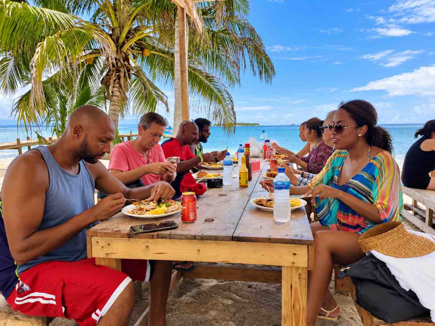 Tour guests eating together at an outdoor beach table