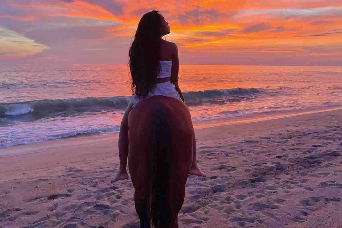 Beach Horseback riding woman riding into red sunset