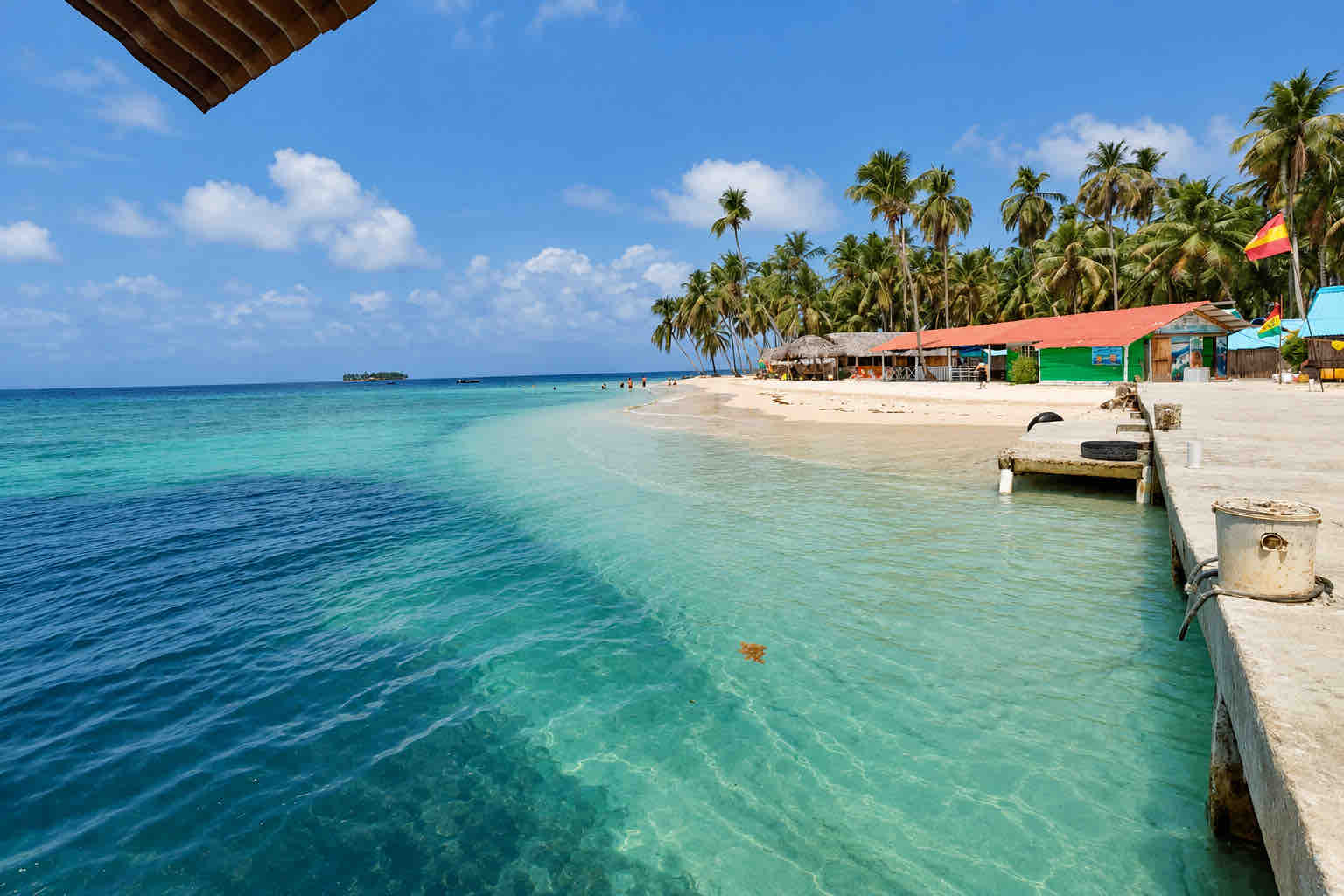 Island arrival dock beside clear water and beach buildings on a San Blas beach trip
