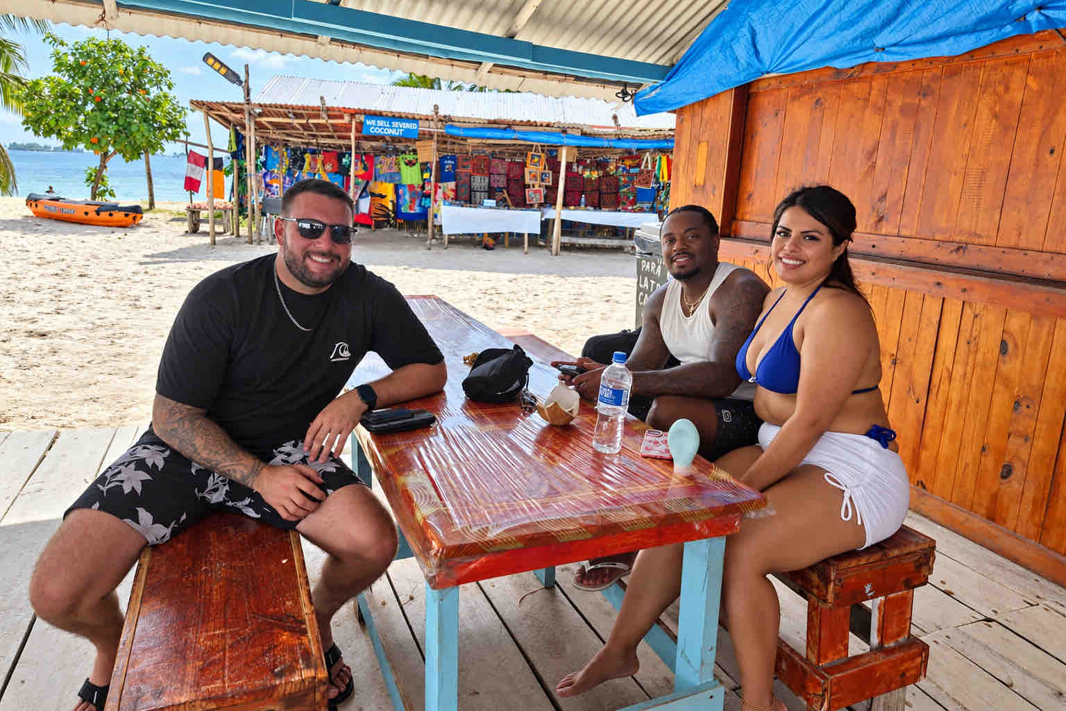 Three travelers seated at a wooden island restaurant table during a San Blas beach trip
