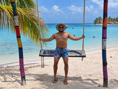 San Blas Beach Trip – Traveler Beach Swing Traveler on a beach swing overlooking turquoise water during a San Blas beach trip