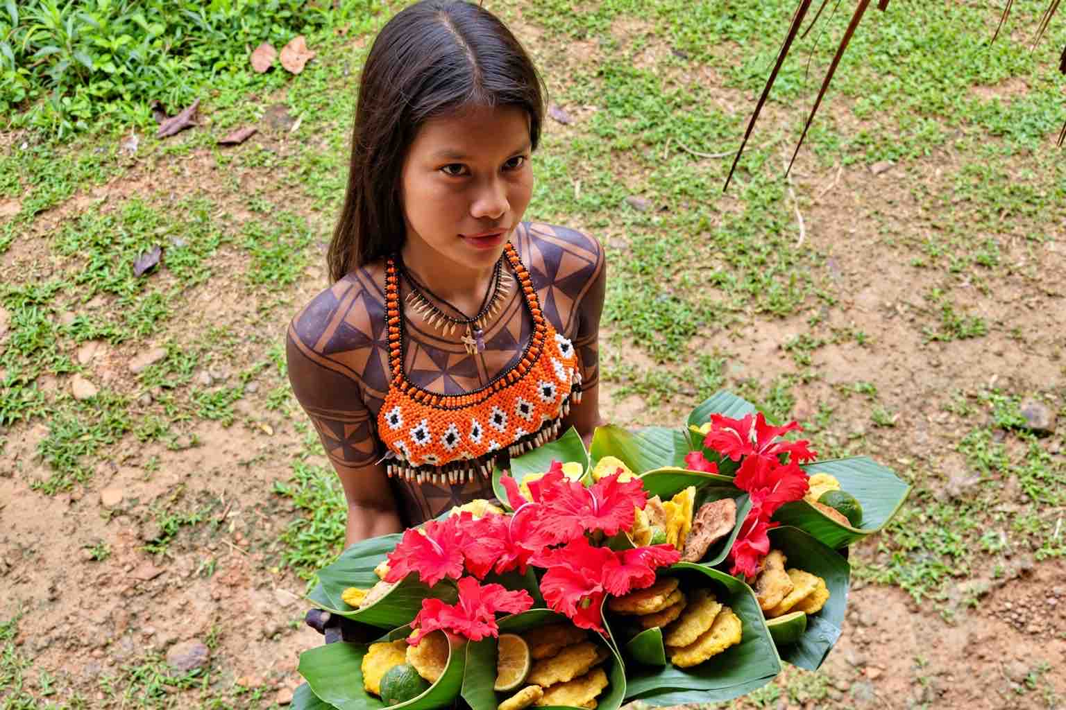 Emberá host holding leaf-wrapped lunches decorated with red flowers