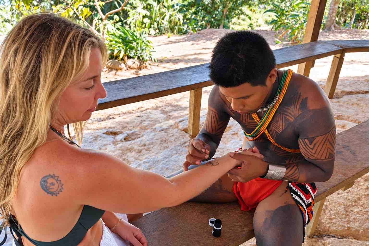 Emberá artist applying a body-paint design to a visitor's forearm