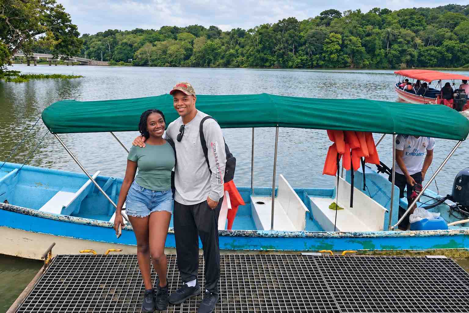 Couple posing beside a covered boat before a Monkey Island boat tour Panama
