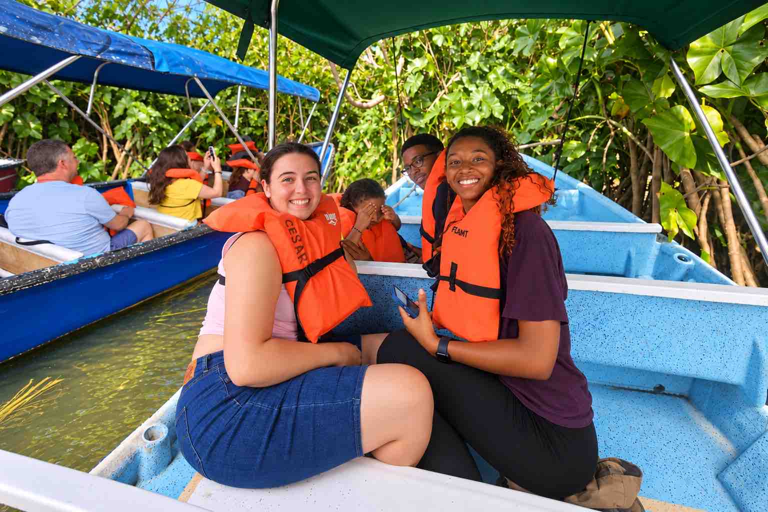 Guests in orange life jackets beside a forested shore on a Monkey Island boat tour Panama