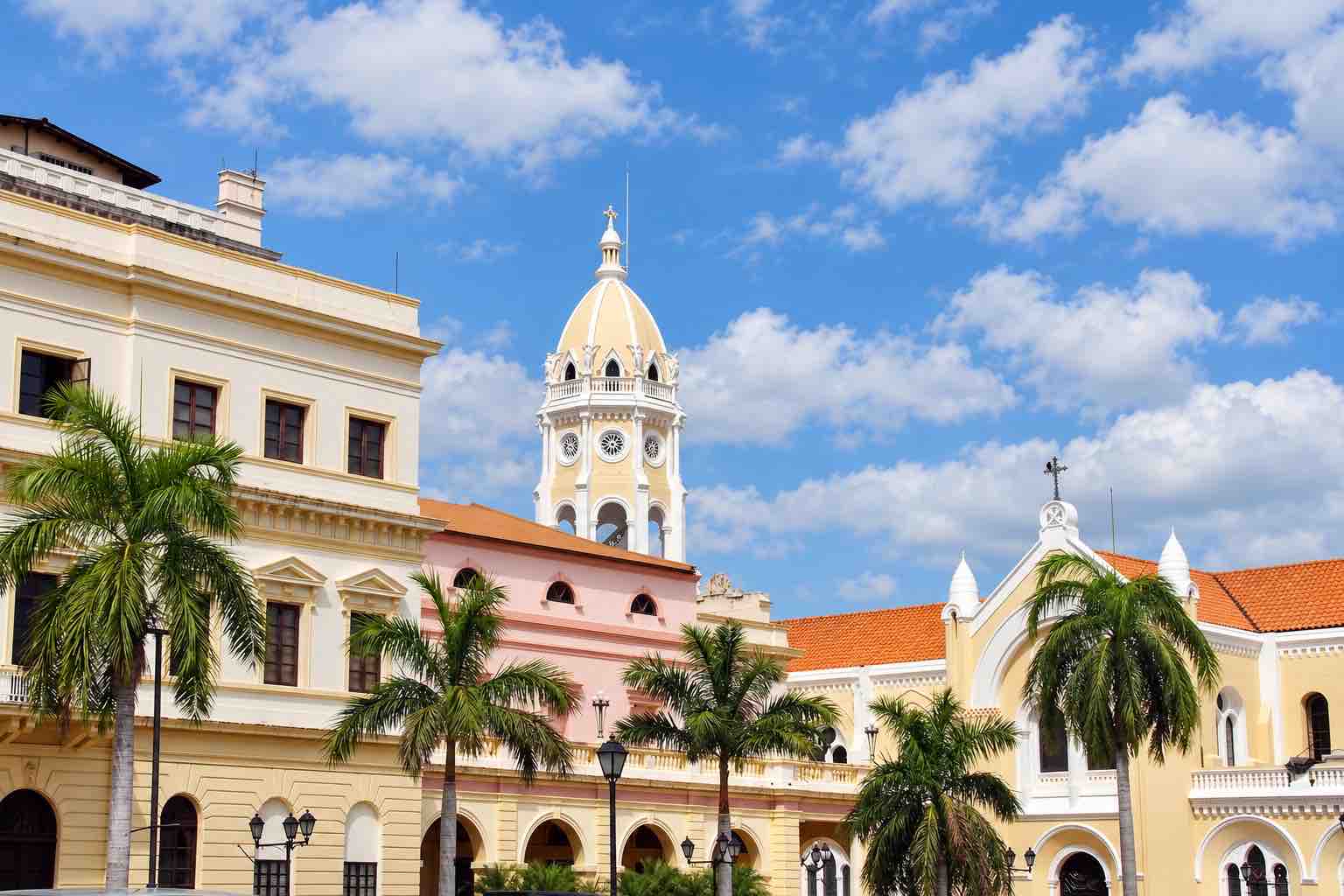 Panama Canal and City Tour: historic buildings, a church tower and palm trees in Casco Antiguo.