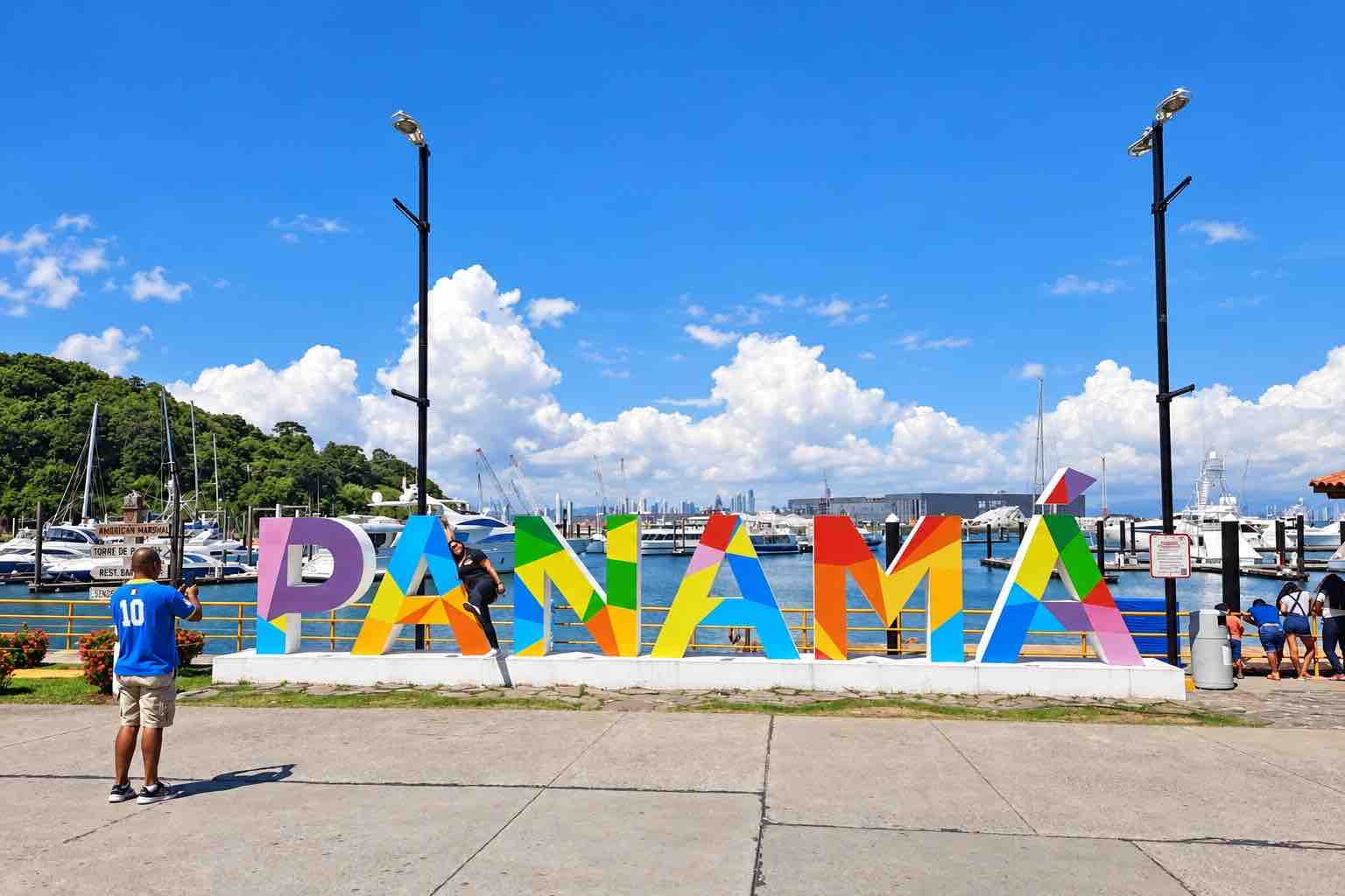 Panama Canal and City Tour: visitors beside the colorful Panama sign under a blue sky.