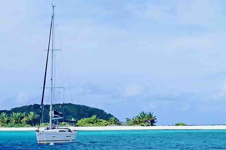 Sailing Ferm anchored on a San Blas island with palm trees and white sand beach