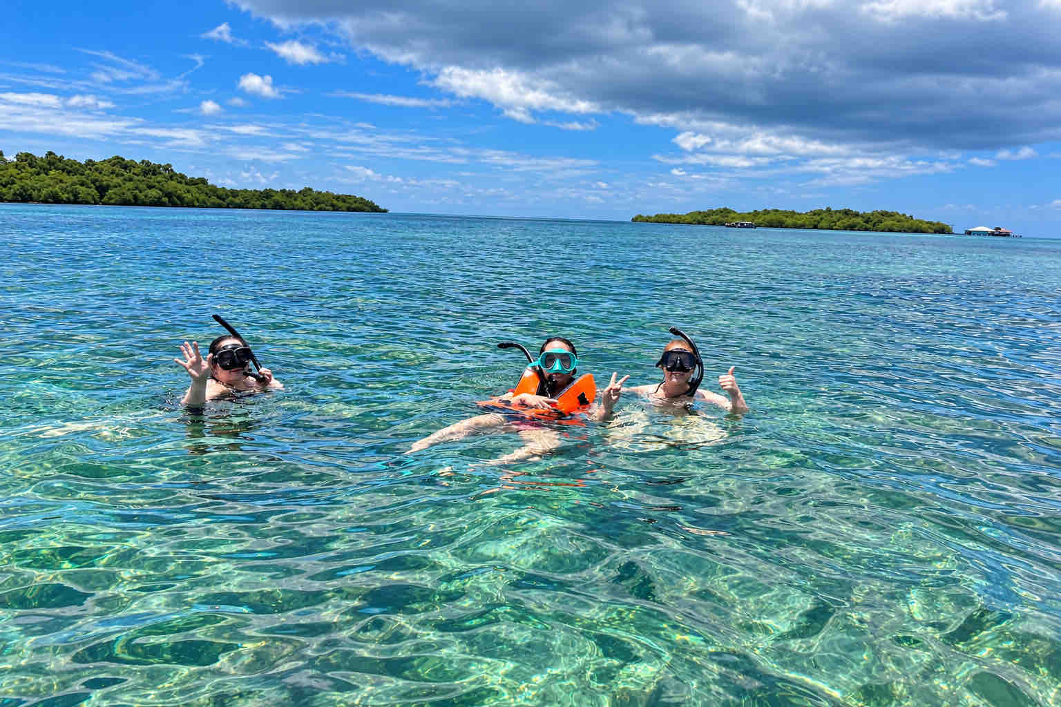 Three travelers wearing snorkel masks in clear water during a Bocas del Toro snorkeling tour.
