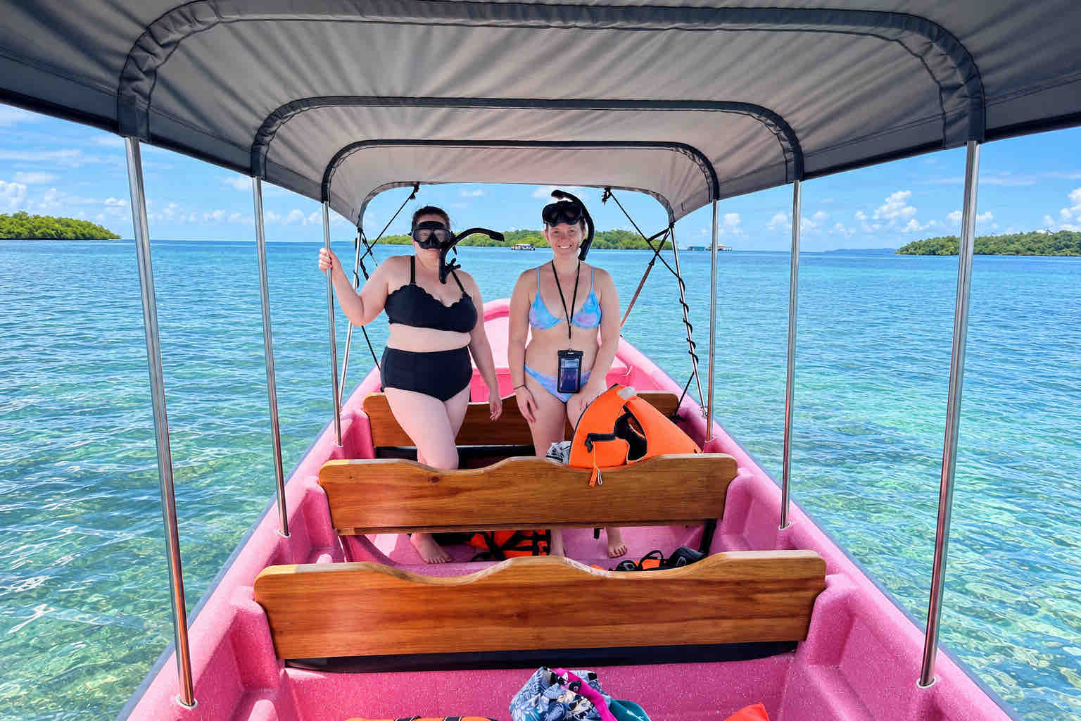 Two travelers wearing snorkel masks aboard a pink covered boat in Bocas del Toro.