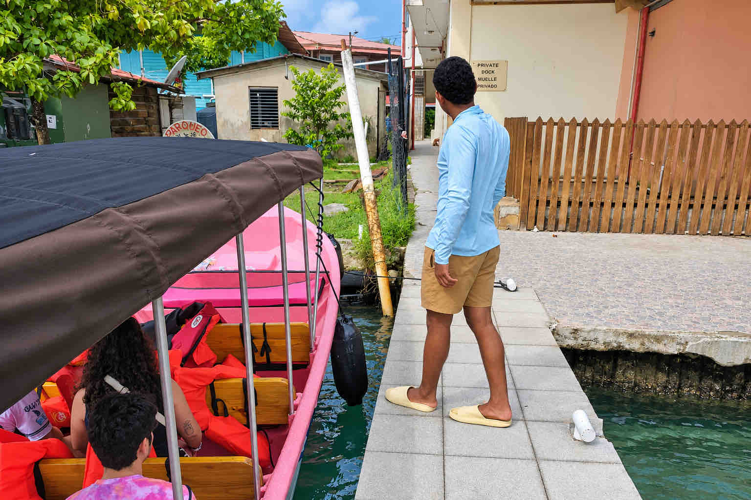 Traveler standing beside a pink covered boat at a Bocas del Toro dock.