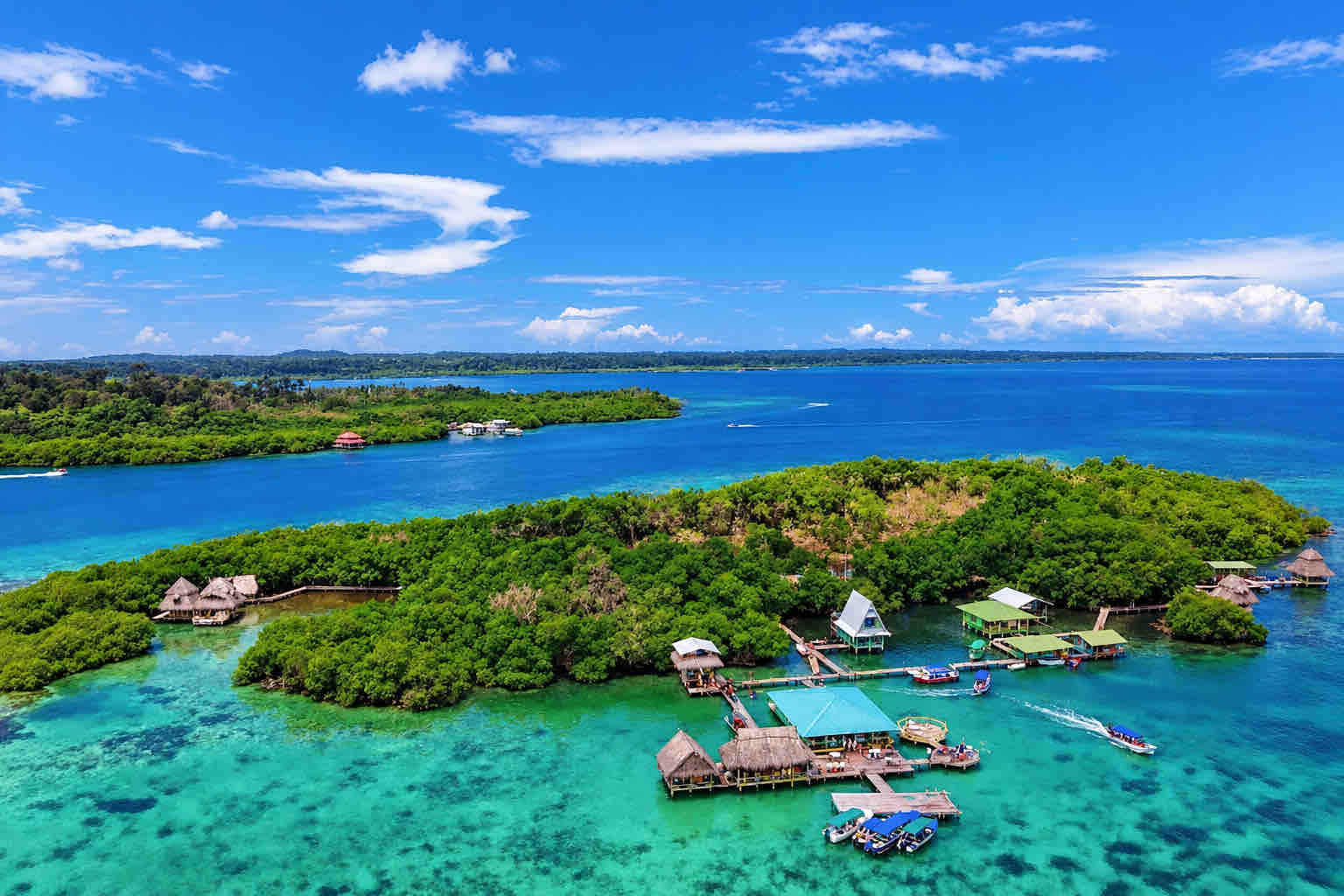 Aerial view of Cayo Coral with mangroves, overwater buildings, docks and boats.
