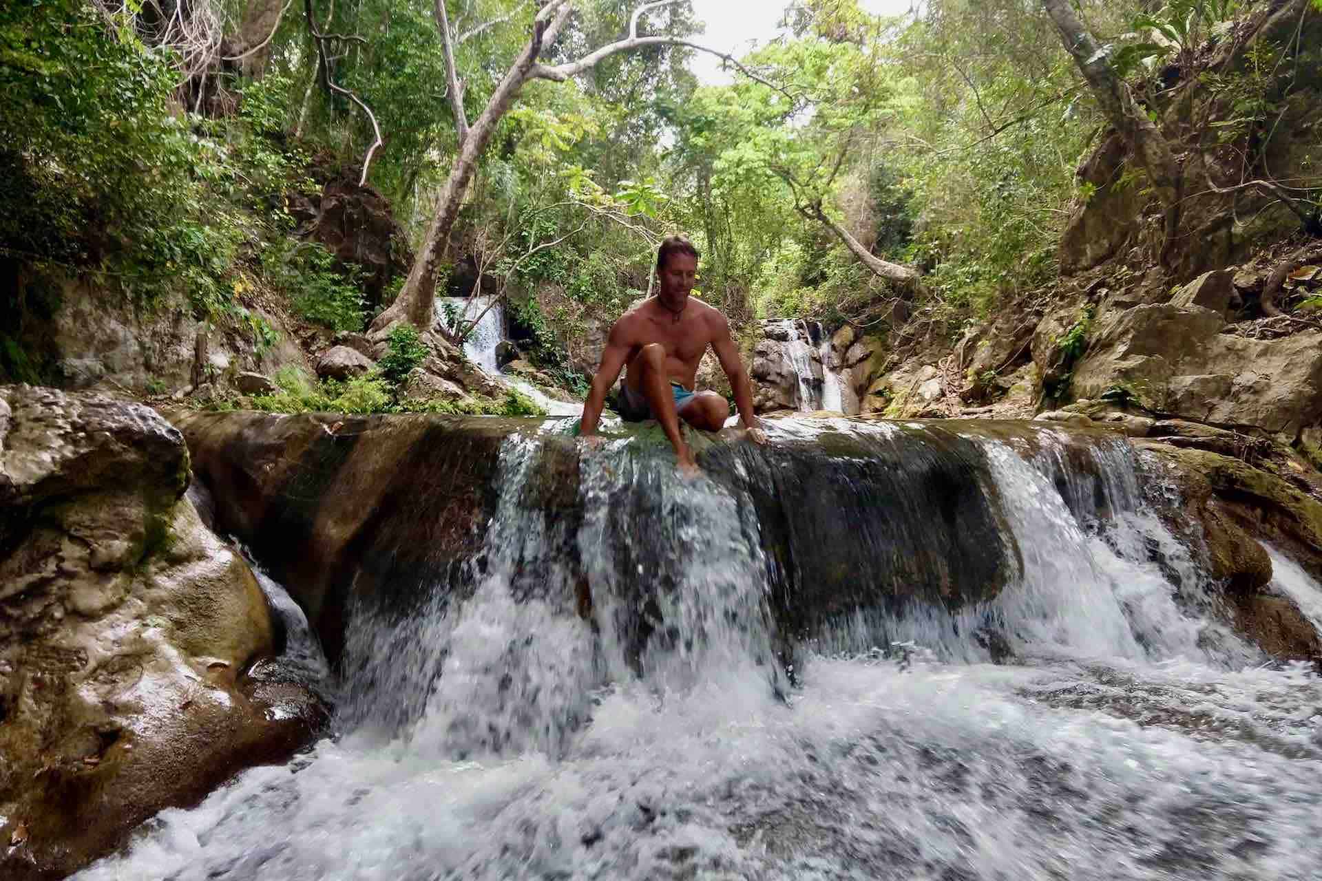 Huatulco waterfalls tour man playing in waterfall stream