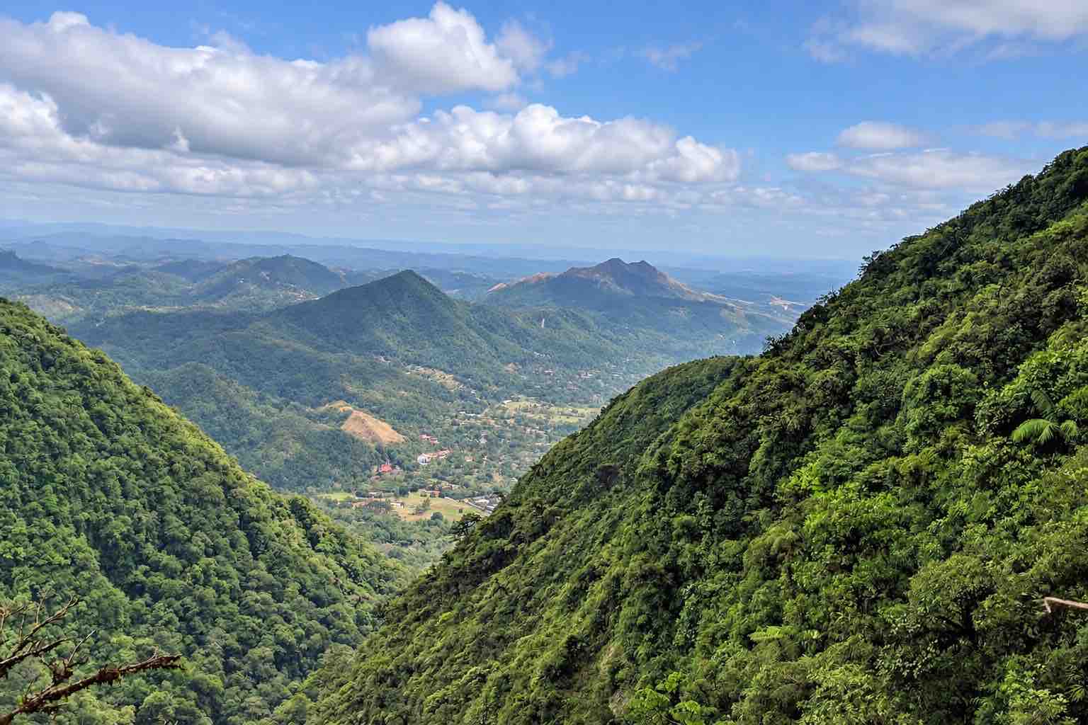 Forested mountain slopes framing a distant view of El Valle de Anton