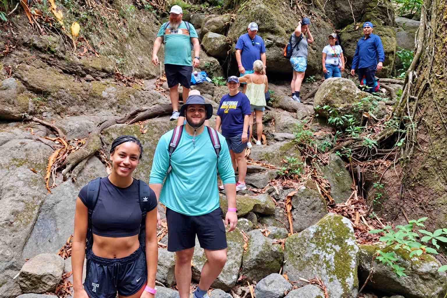 Group of hikers standing among rocks on a wooded trail