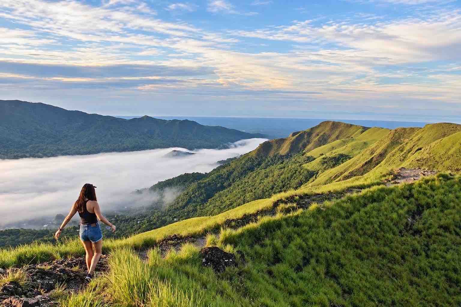 Traveler overlooking grassy mountain ridges and low clouds