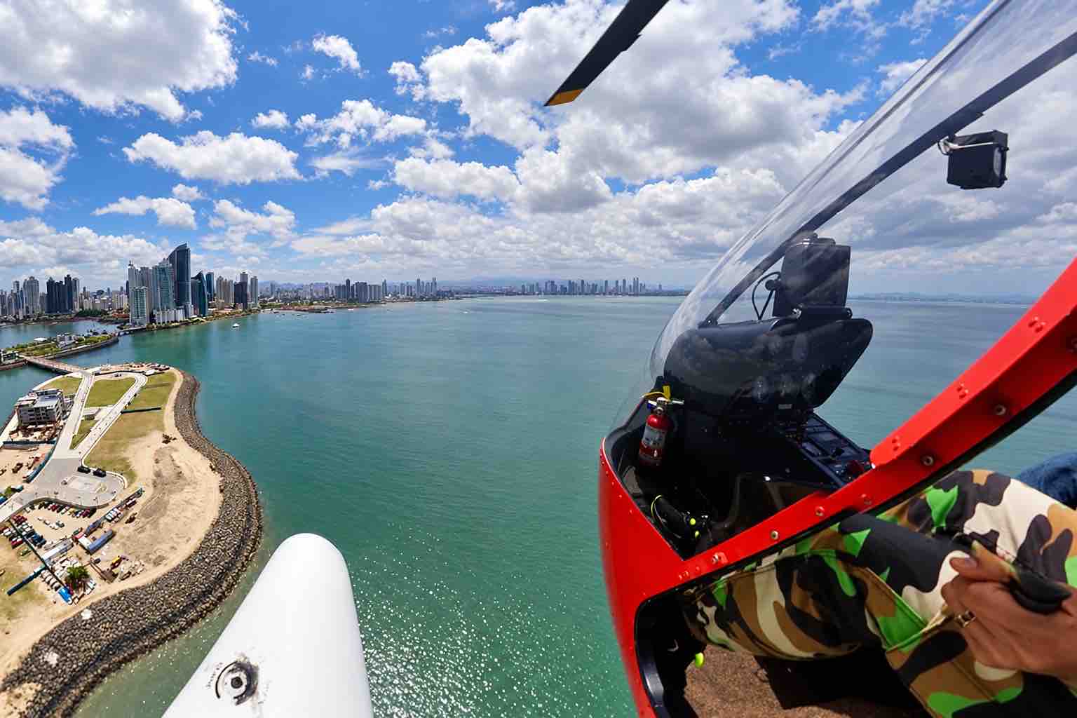 Panama helicopter tour: Helicopter cockpit beside Panama City’s coastal skyline and bay.