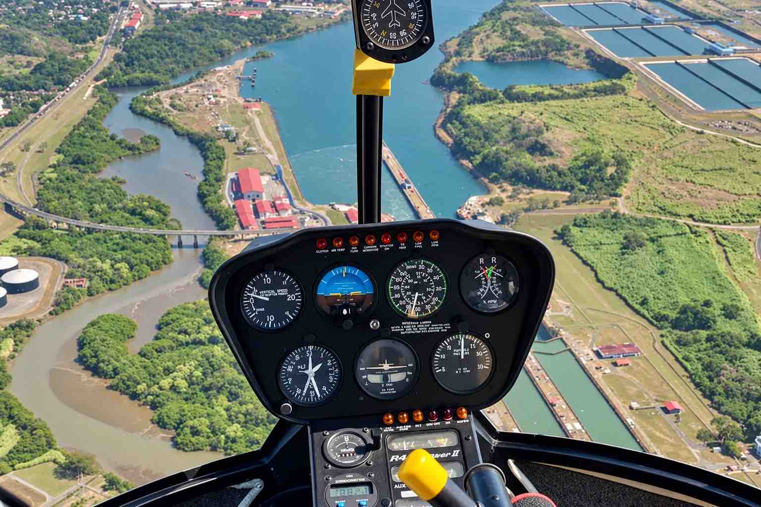 Panama Helicopter Tour – Cockpit Canal Locks Panama helicopter tour: Helicopter instrument panel with canal locks and water basins below.