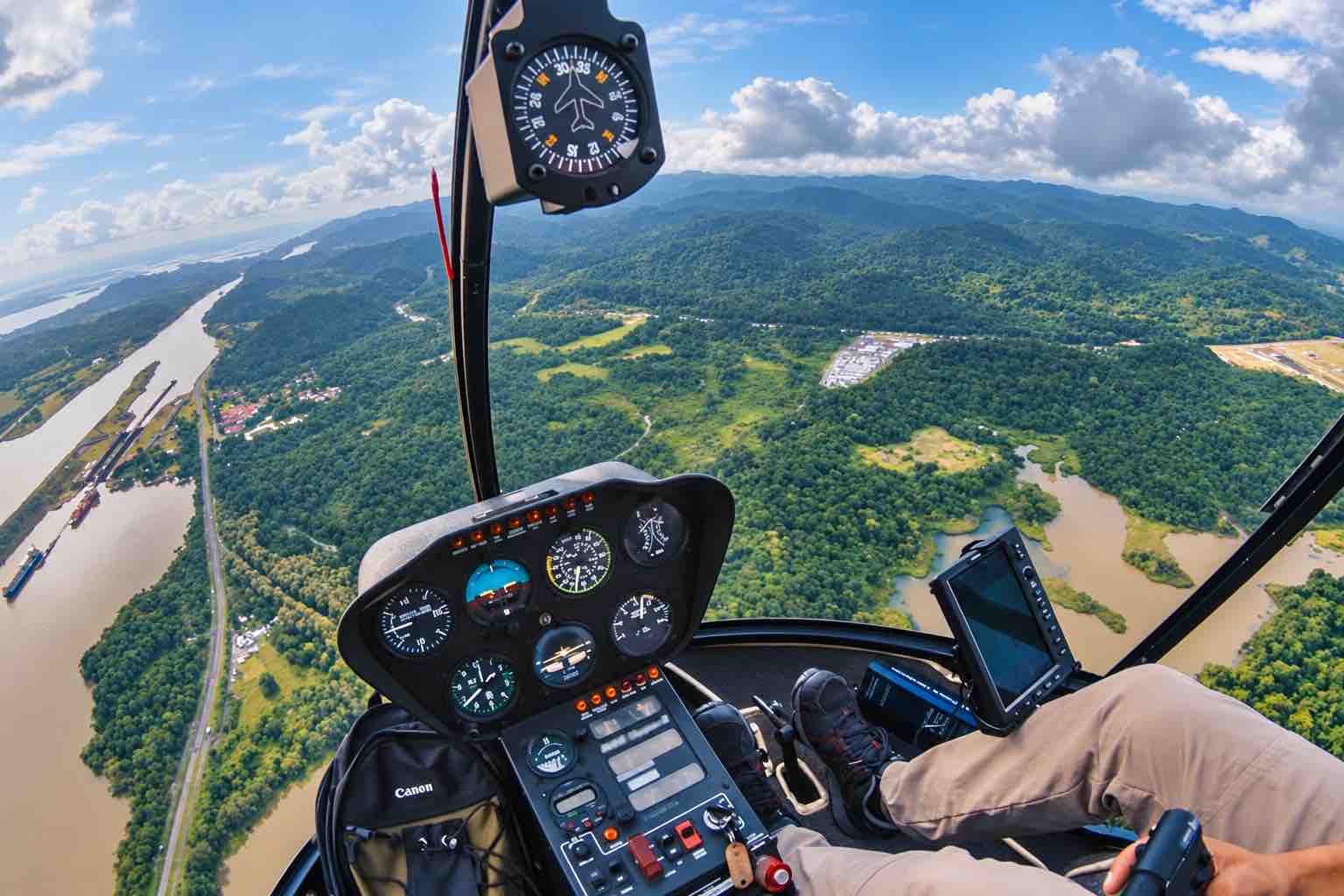 Panama helicopter tour: Helicopter instruments with canal waterways and rainforest beyond the windshield.