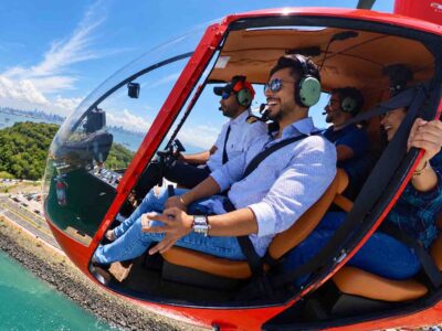 Panama helicopter tour: Guests and pilot wearing headsets in a red helicopter above the coast.