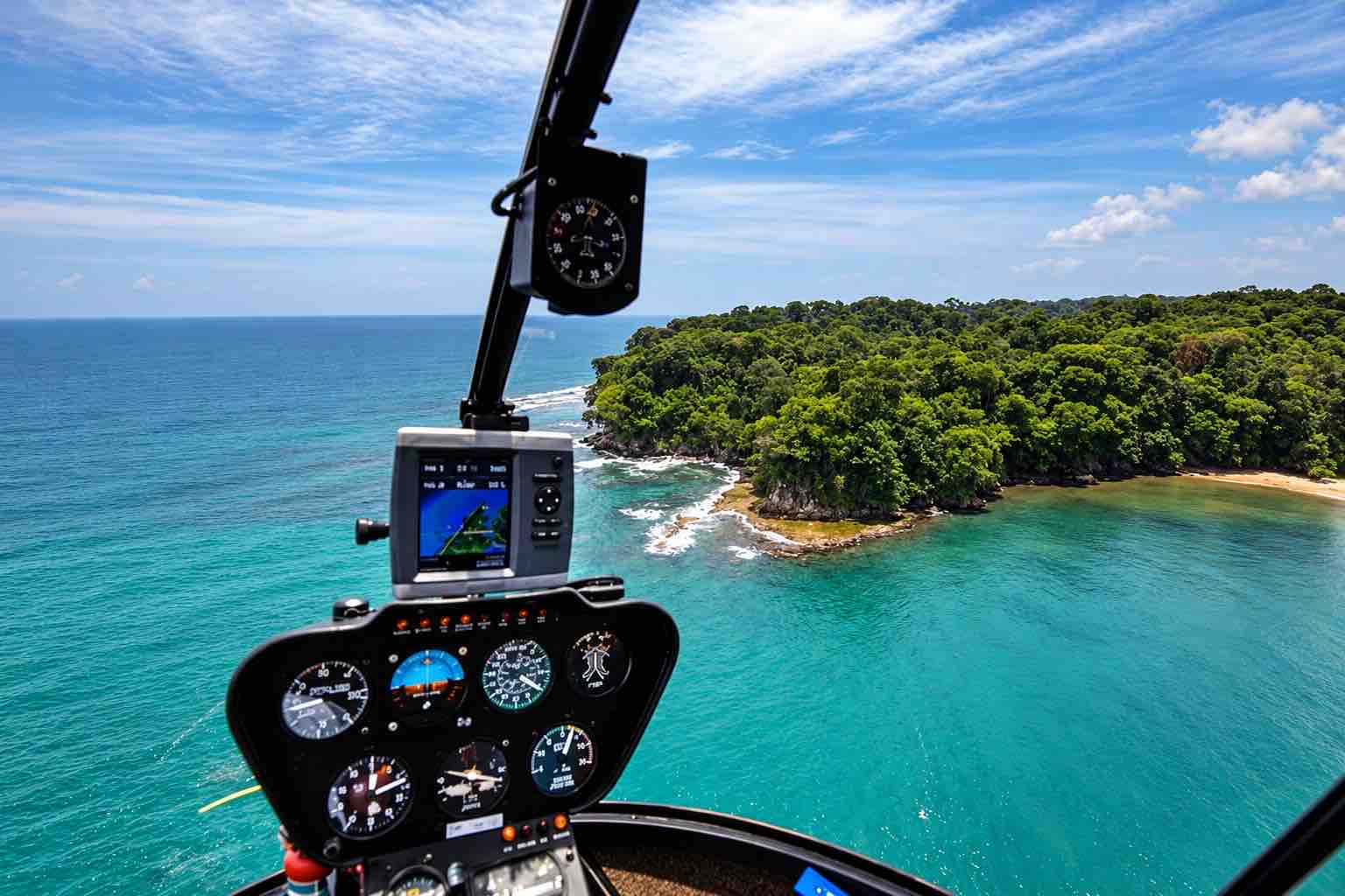 Panama helicopter tour cockpit overlooking a forested island and a turquoise coastal bay.