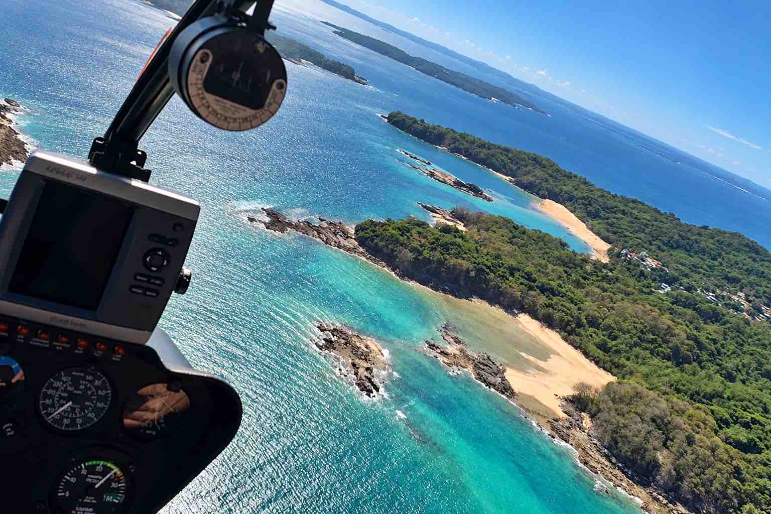 Panama helicopter tour: Wooded islands and sandy beaches viewed through a helicopter windshield.