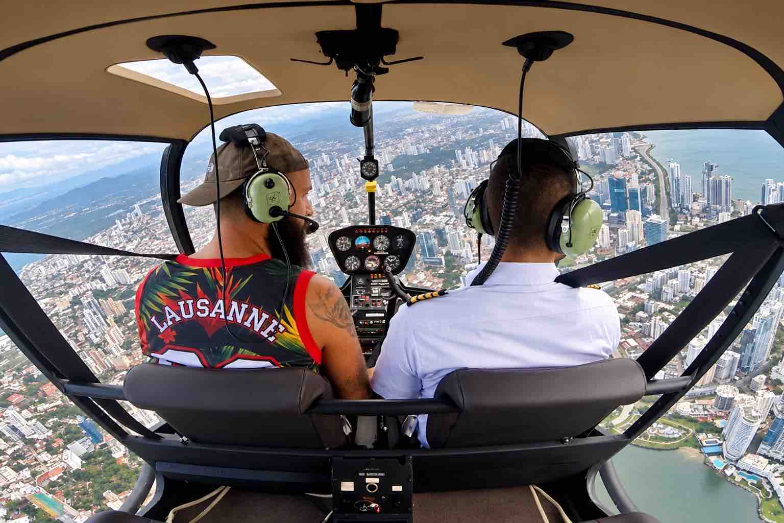 Panama helicopter tour: Passenger and pilot wearing headsets with Panama City below the helicopter.