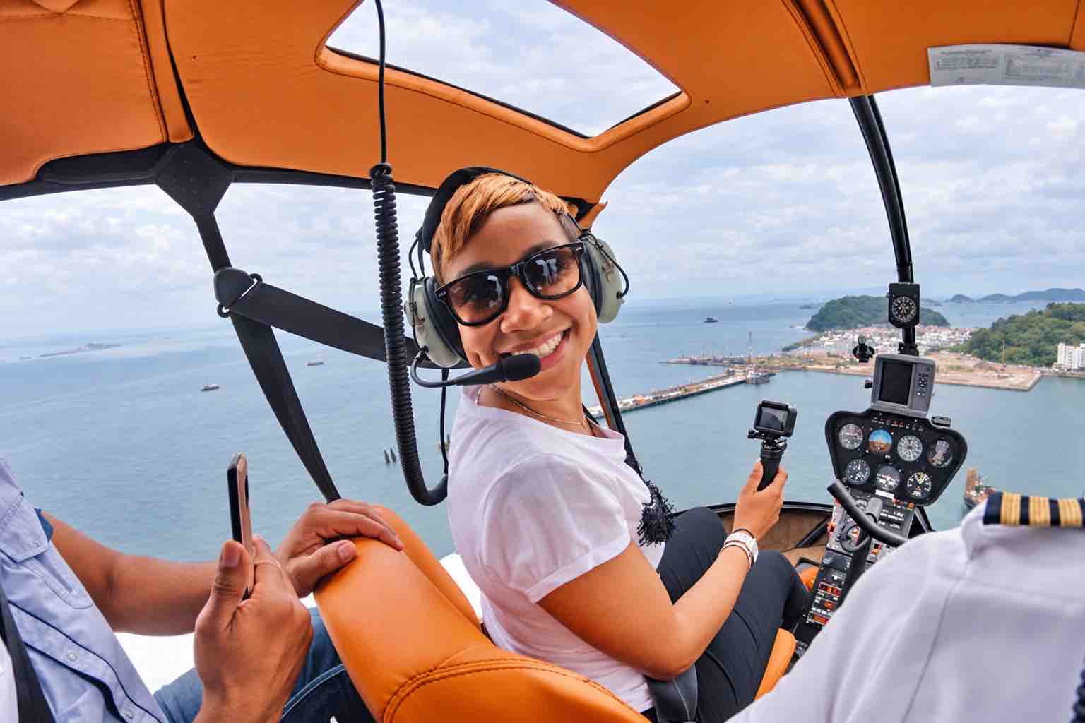 Panama helicopter tour: Smiling passenger wearing a headset and holding a camera inside a helicopter.