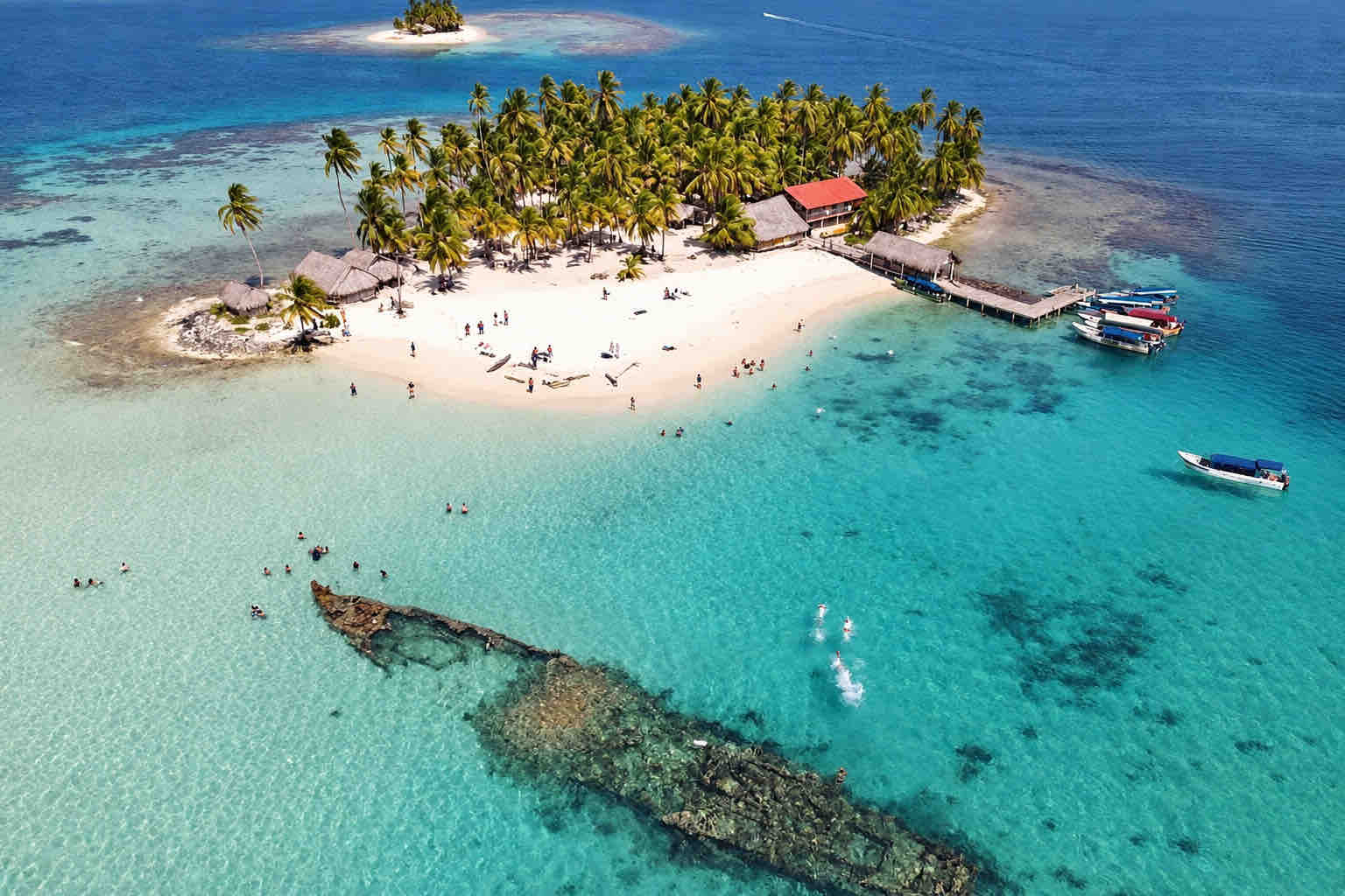 Oblique aerial view of the island beach, dock and nearby shipwreck at Isla Perro San Blas