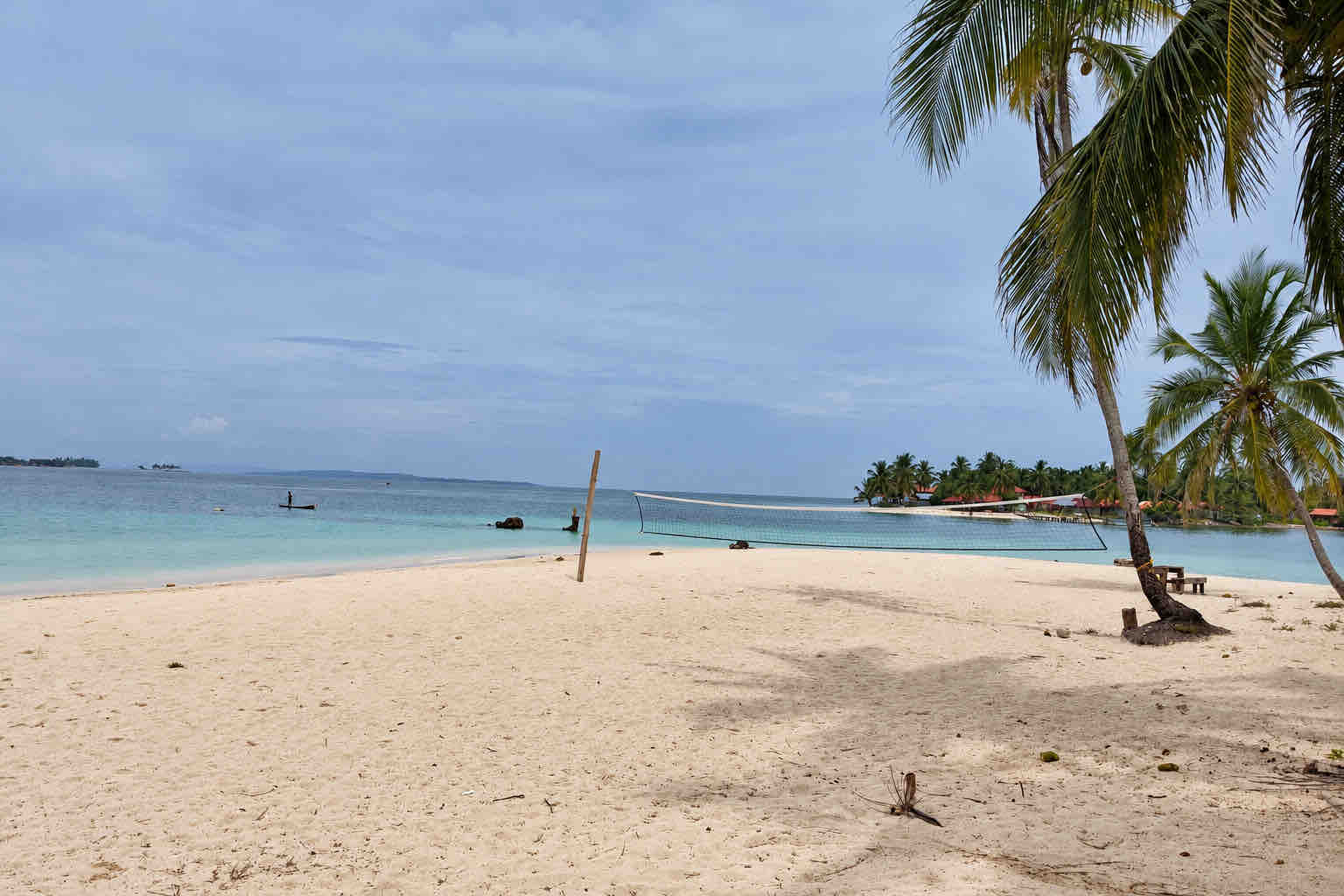 Volleyball net on the sandy main beach with palms and clear water at Isla Perro San Blas