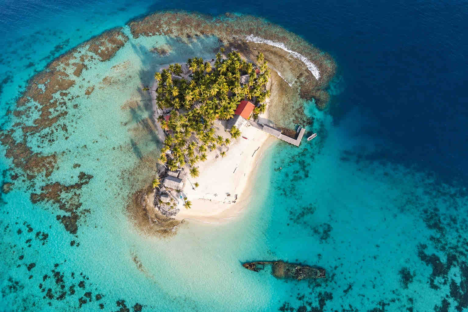 Overhead aerial view of Isla Perro with its beach, reef, dock and shipwreck at Isla Perro San Blas