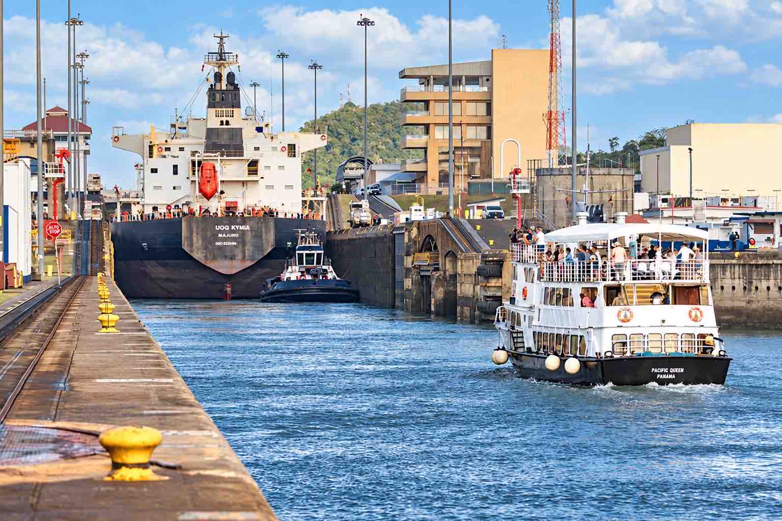Panama Canal partial transit tour: passenger boats sharing a canal lock chamber with a cargo ship.