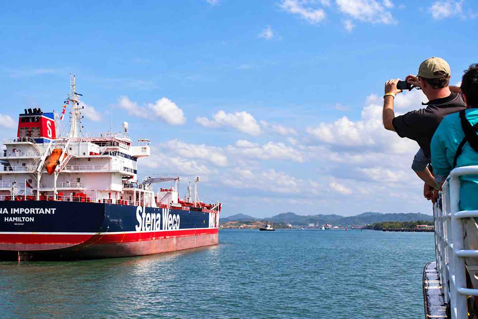 Panama Canal partial transit tour: a guest photographing a passing cargo ship from the cruise boat.