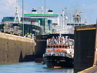Panama Canal partial transit tour: a passenger boat inside a canal lock ahead of a cargo ship.
