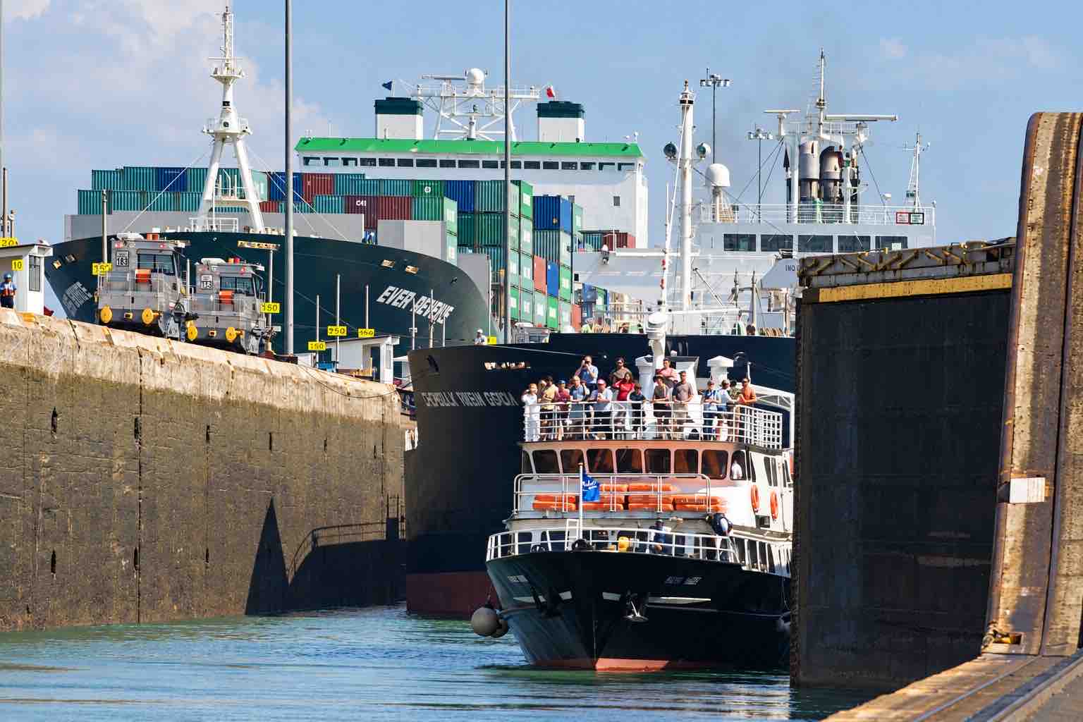 Home Elementor 11 Panama Canal partial transit tour: a passenger boat inside a canal lock ahead of a cargo ship.