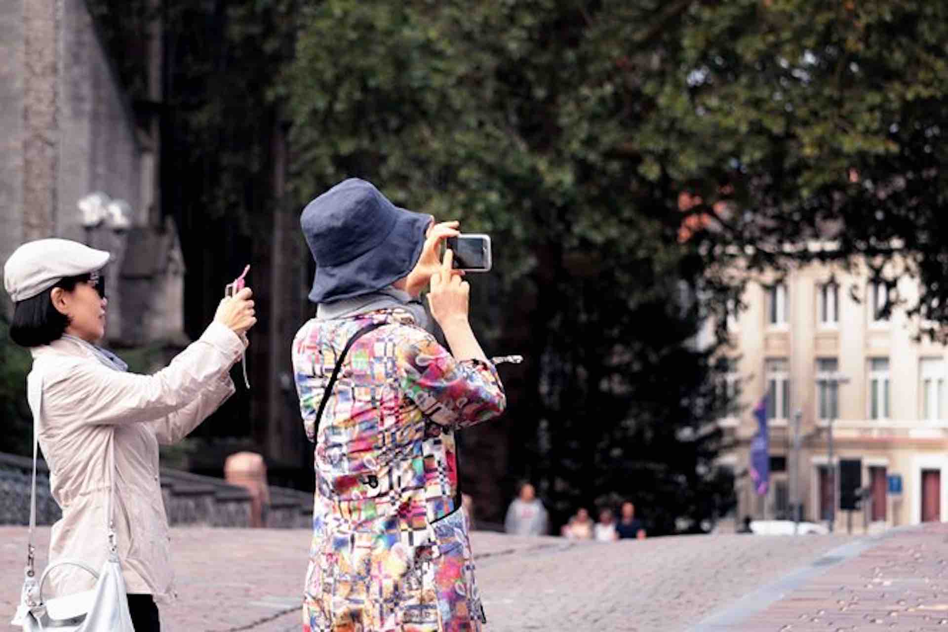 Casco Viejo Walking Tour image: two visitors photographing buildings from a shaded plaza