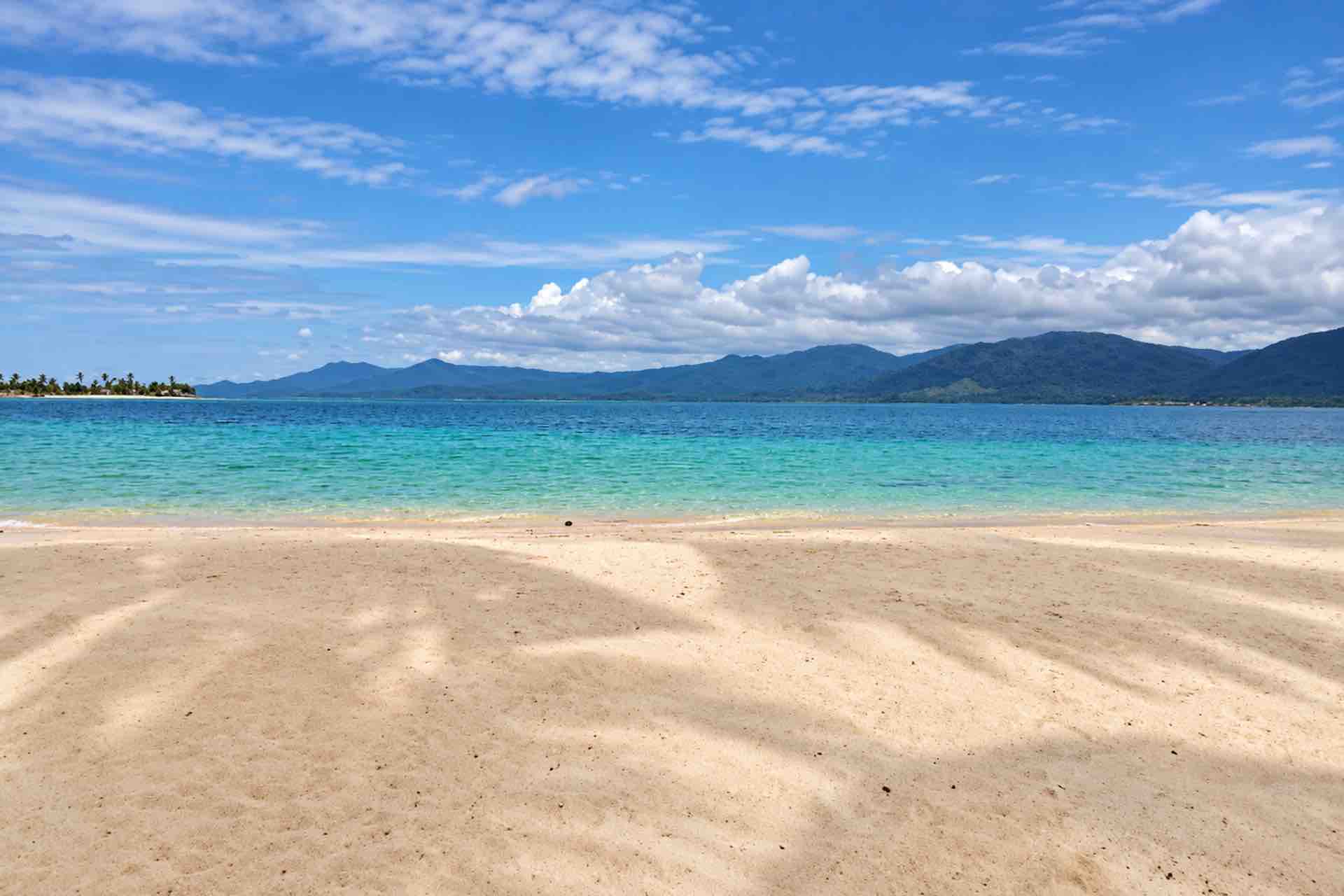 Sandy beach and turquoise sea on Isla Ina in San Blas