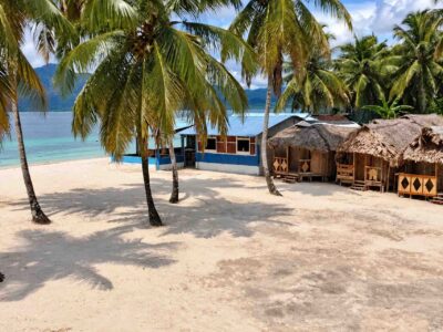 Palm trees and cabins beside the beach on Isla Ina in San Blas