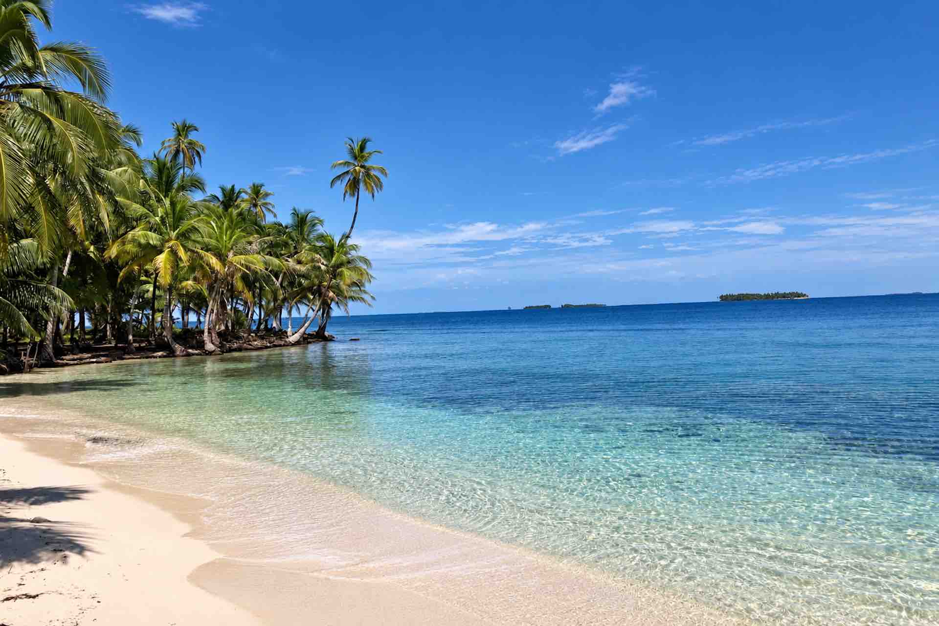 Palm-fringed white sand beach and turquoise water on Isla Ina