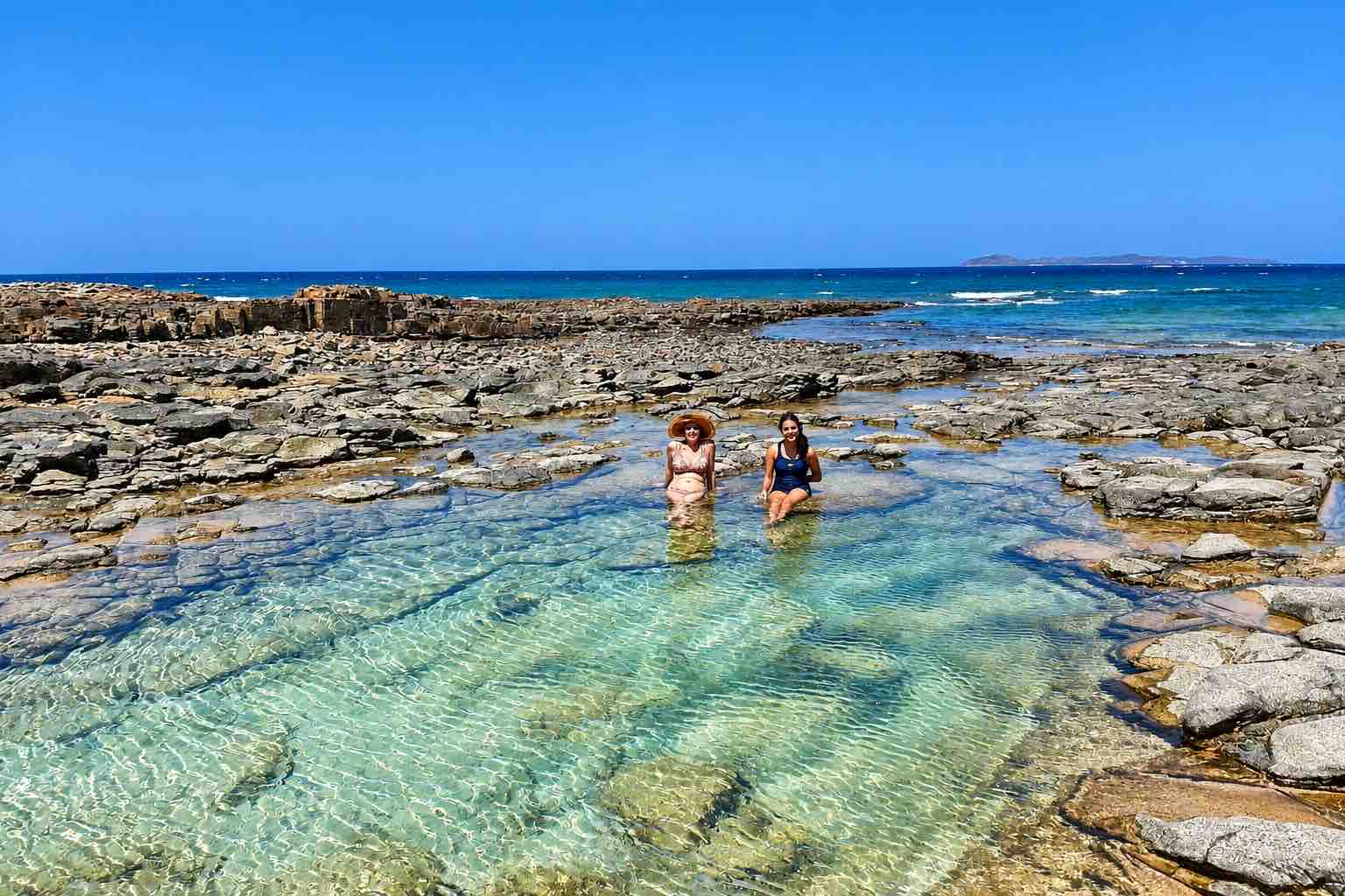 Two guests relaxing in a rocky tide pool during a Pearl Islands Panama Day Trip